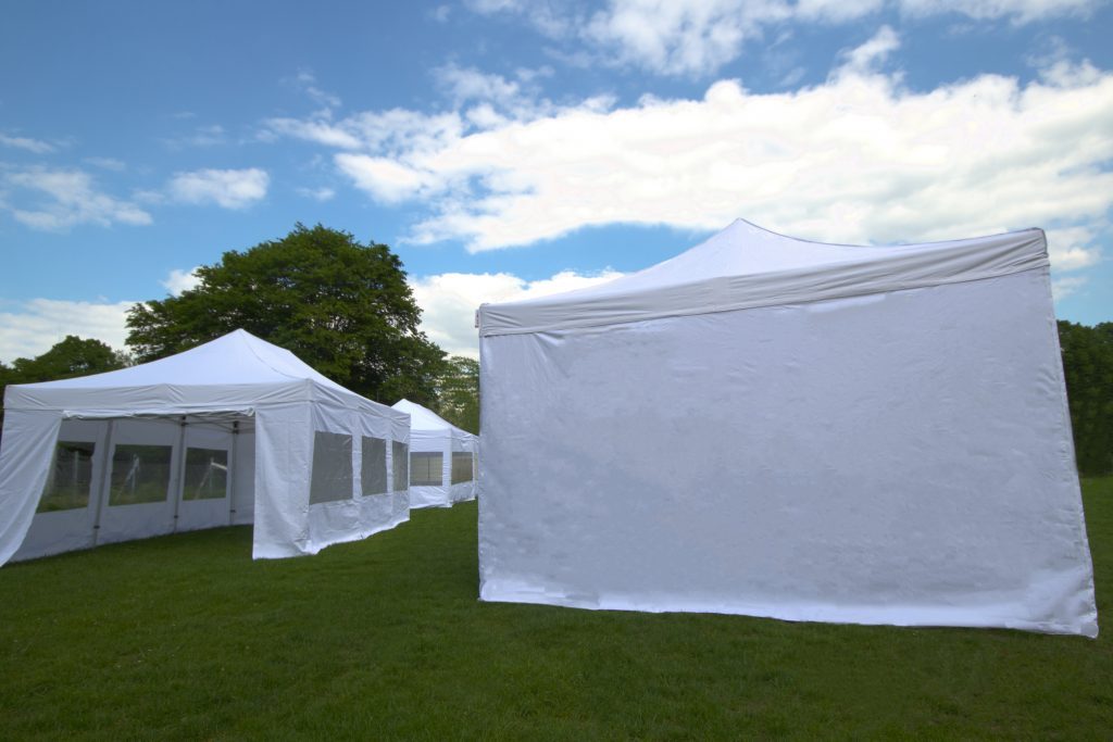 Weißes Garten-Partyzelt mit Fensterplanen auf einer Wiese